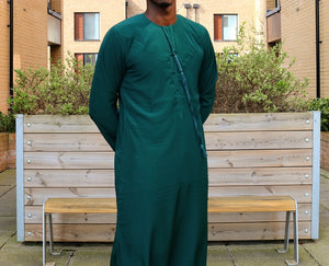 A man wearing an emerald green emirati thobe
