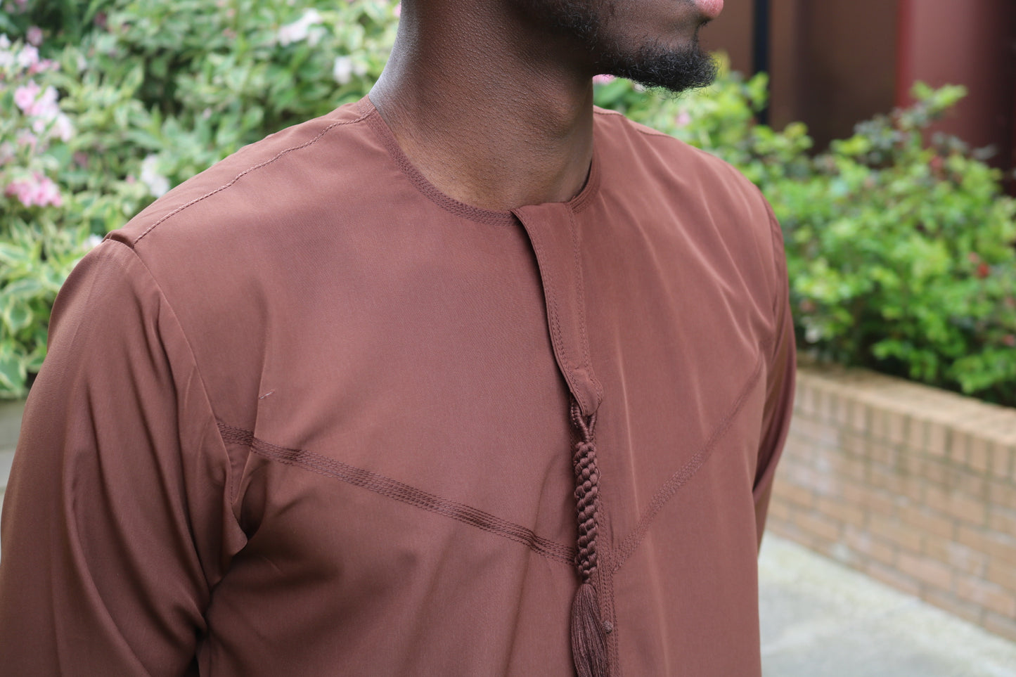 A man wearing a chocolate brown emirati thobe