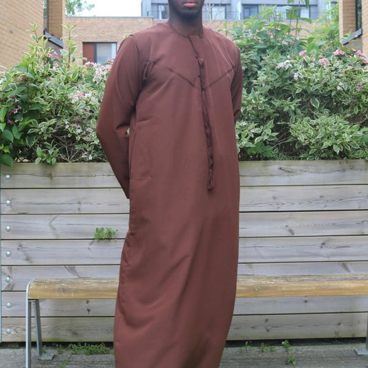 A man wearing a chocolate brown emirati thobe