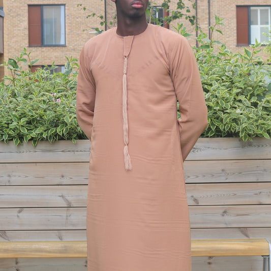 A man wearing a camel brown emirati thobe