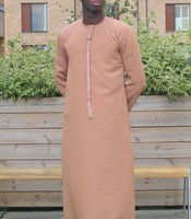 A man wearing a camel brown emirati thobe