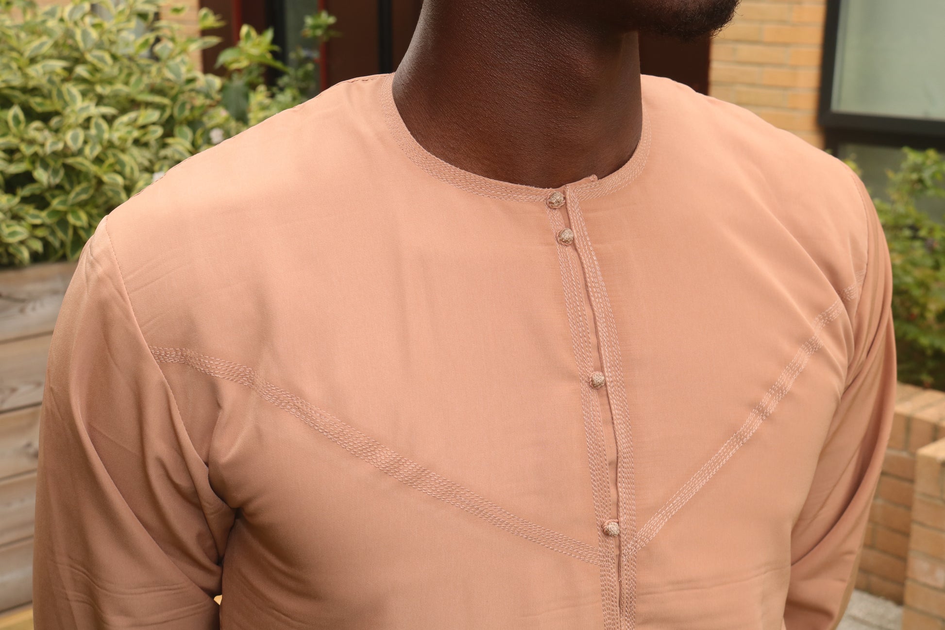 A man wearing a camel brown emirati thobe