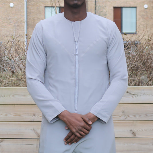 A man wearing a grey emirati thobe