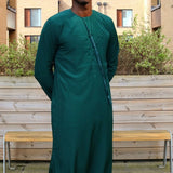 A man wearing a emerald green emirati thobe
