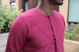 A man wearing a rosewood maroon emirati thobe