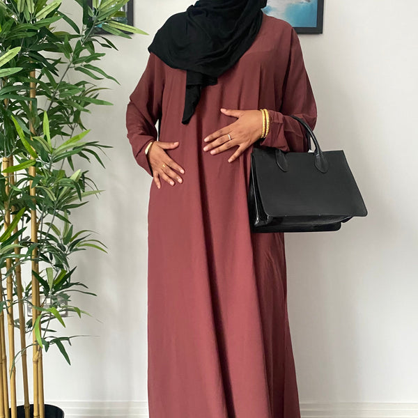 A woman wearing a simple rosewood maroon abaya