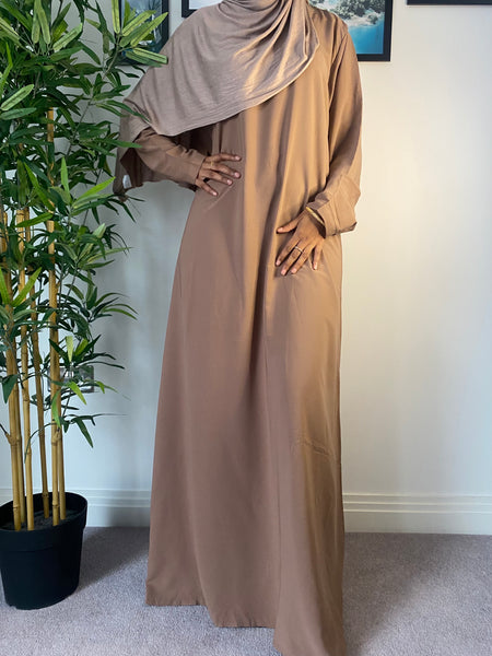 A woman wearing a simple camel brown abaya