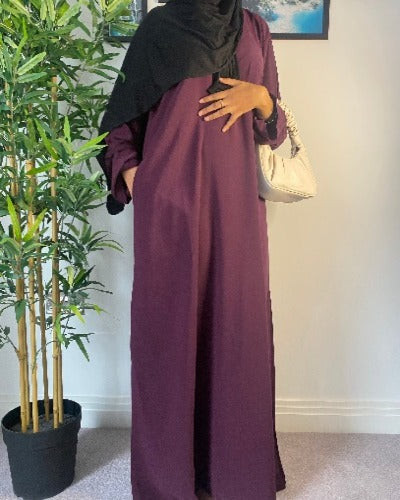A woman wearing a simple plum purple abaya