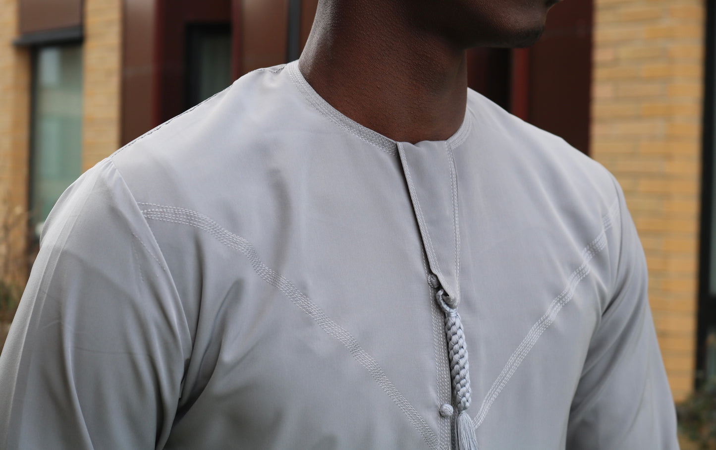 A man wearing a grey emirati thobe
