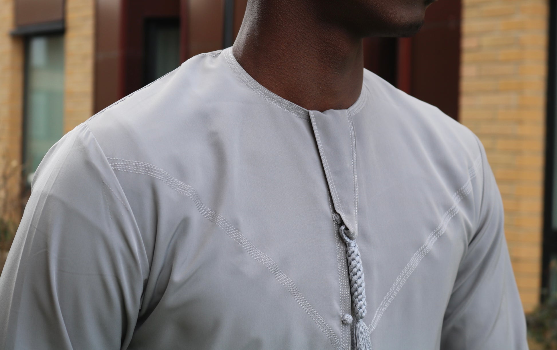 A man wearing a grey emirati thobe