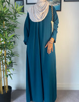 A woman wearing a simple teal abaya