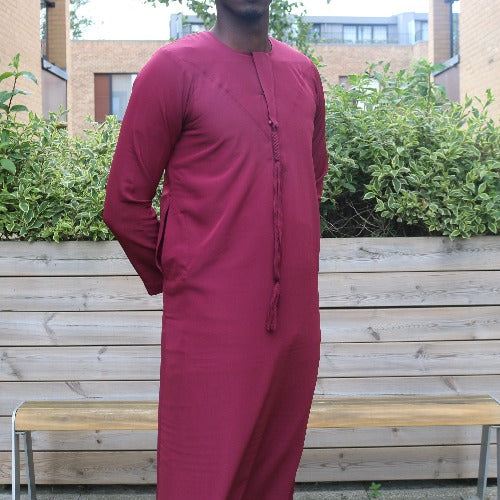 A man wearing a rosewood maroon emirati thobe